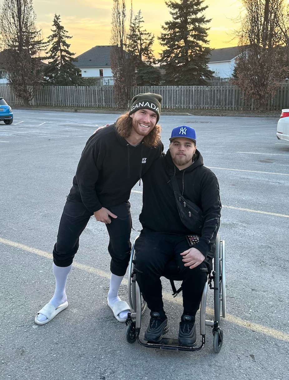 Gavin Smith in his wheelchair with Brandon Peacock at sunset — defying the odds after a spinal gunshot wound