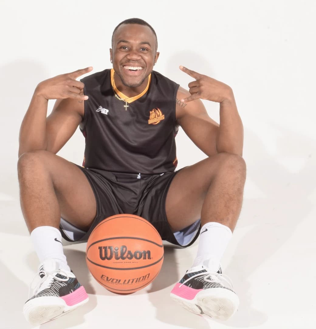 Michael Otoo sitting with a Wilson basketball, smiling — back on the court after his traumatic brain injury